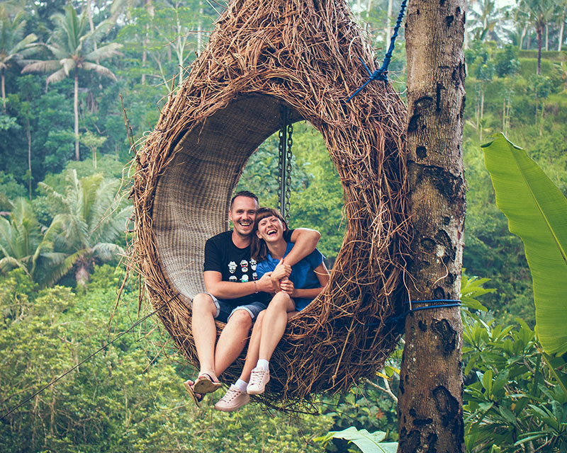 Image of happy travellers sitting in a wicker seat in the jungle in Bali, Indonesia